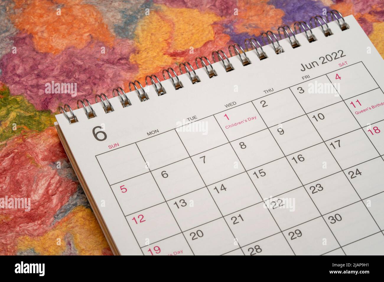 Juni 2022 - Spiral Desktop Kalender gegen helle bunte handgemachte Papier-, Zeit-und Geschäftskonzept Stockfoto