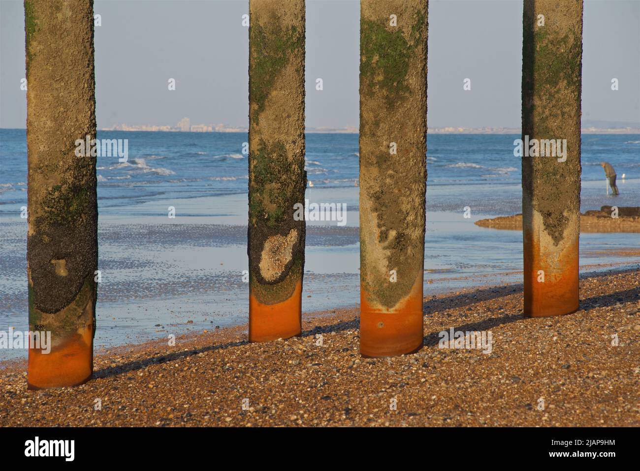 Vier vertikale Eisensäulen erheben sich vom Strand an der Stelle des historischen West Pier-Gebäudes, das nach seiner Schließung im Jahr 1975 verfiel und verloren ging. Gezeiten Niedrig. Brighton, East Sussex, England, Großbritannien. Worthing am fernen Horizont. Stockfoto