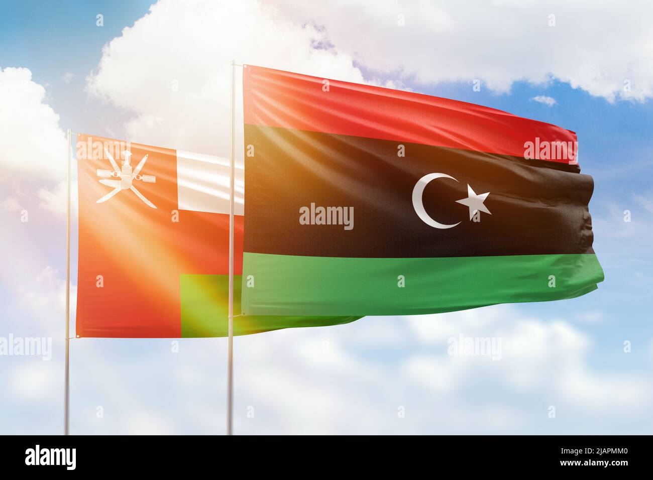 Sonniger blauer Himmel und Flaggen von libyen und oman Stockfoto