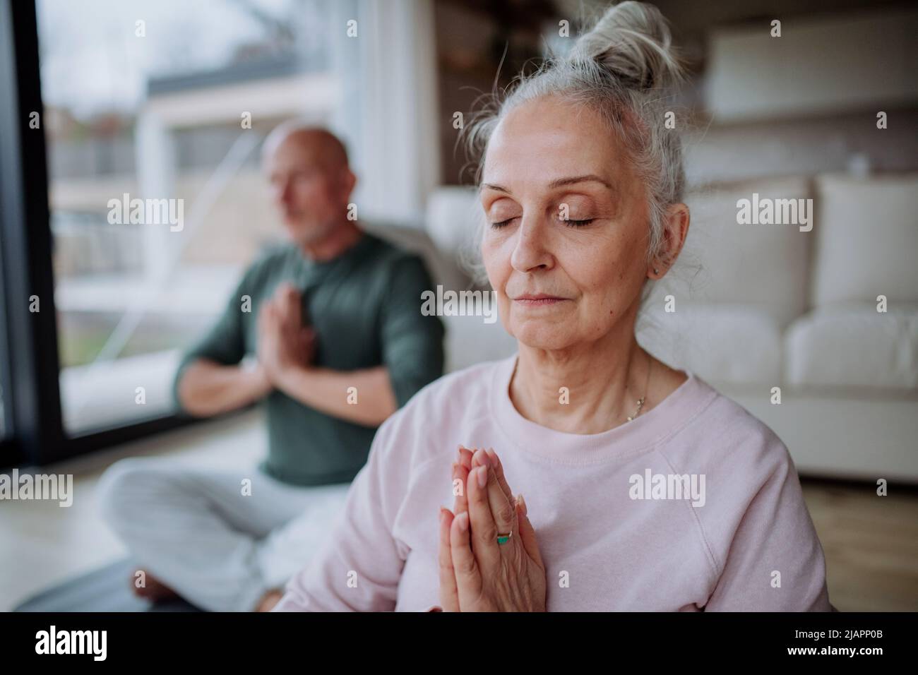 Seniorenpaar macht zu Hause gemeinsam Entspannungsübungen. Stockfoto