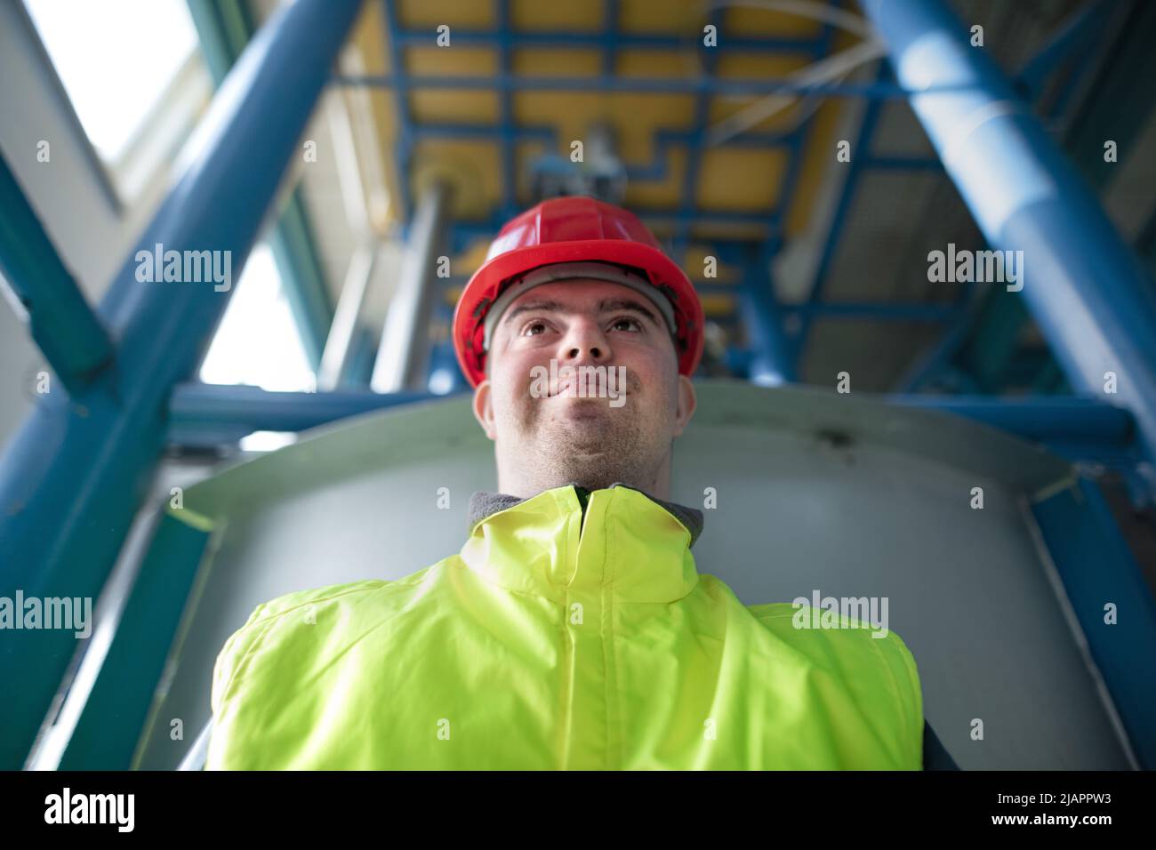 Junger Mann mit Down-Syndrom arbeitet in der industriellen Fabrik, soziale Integration Konzept. Stockfoto