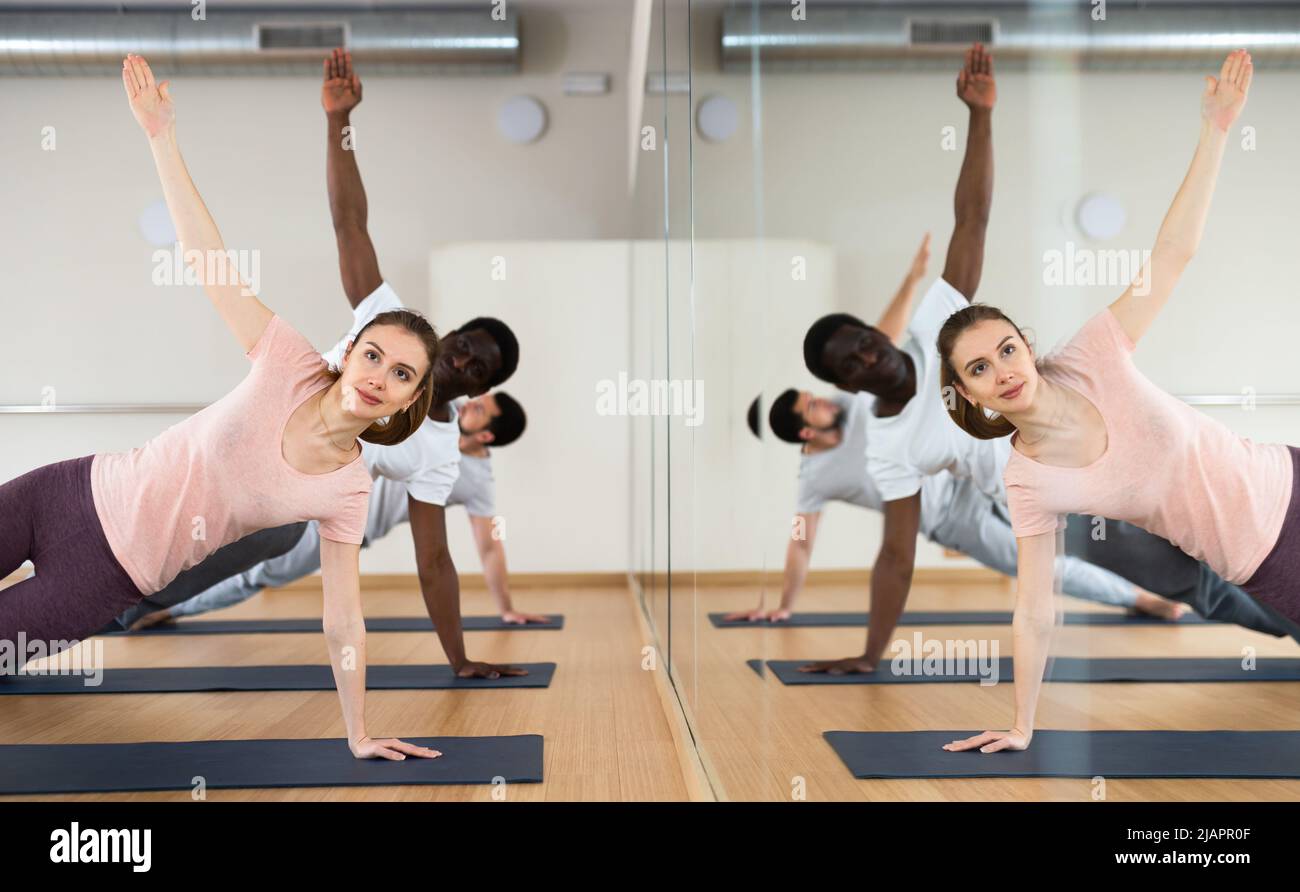 Frau, die in Vasisthasana in der Nähe des Spiegels mit Spiegelung steht Stockfoto