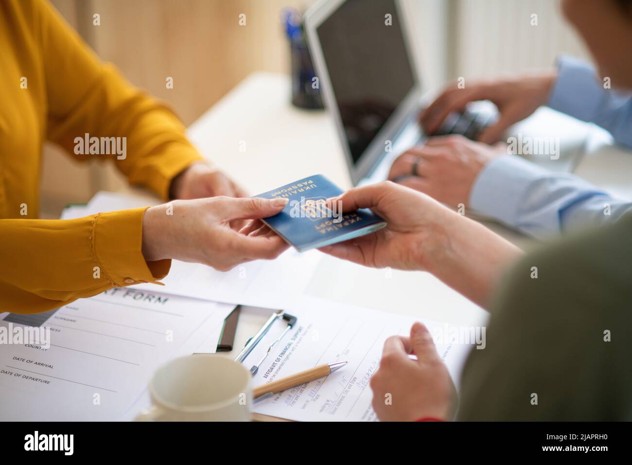 Freiwillige Helferinnen von Frauen und Männern, die der ukrainischen Frau beim Ausfüllen von Formularen im Asylzentrum helfen. Stockfoto