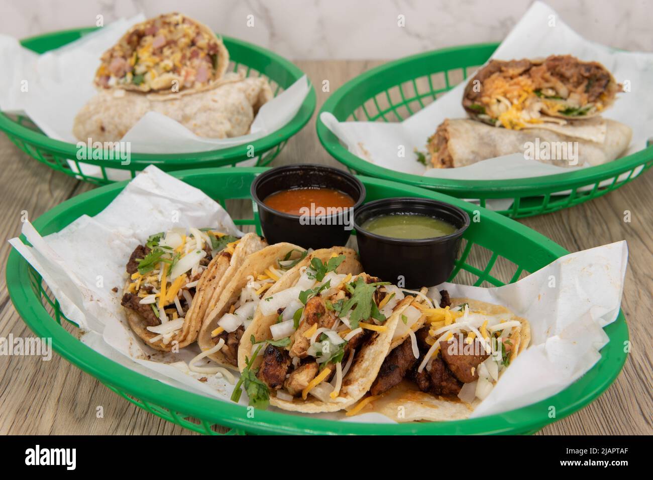Auf diesem Tisch stehen viele Tacos voller köstlicher mexikanischer Küche, die in einem Fast-Food-Korb serviert werden. Stockfoto