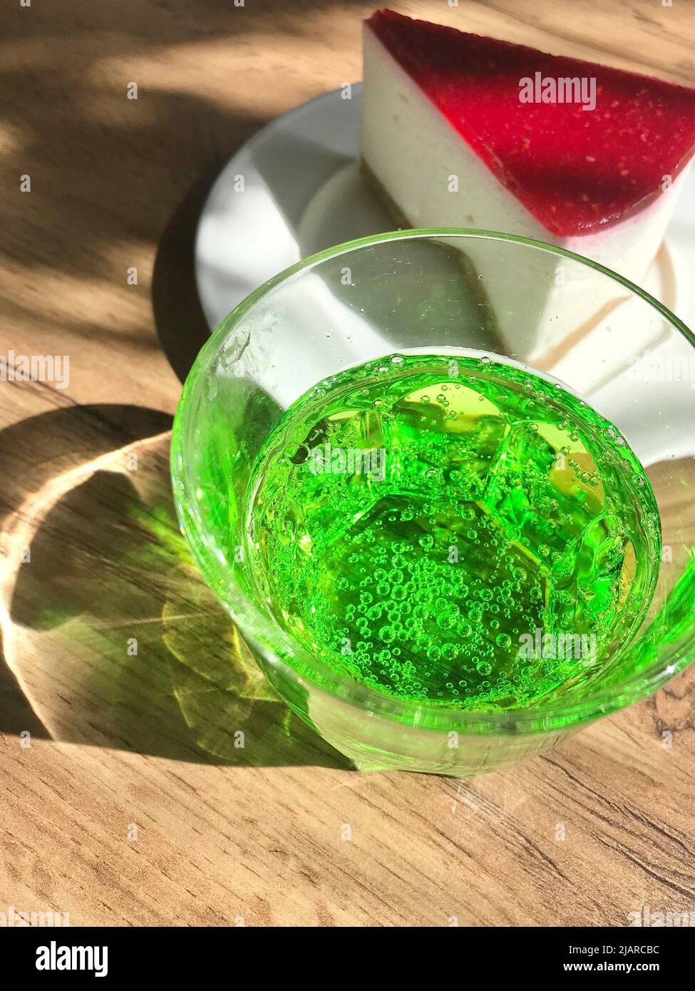 Grünes Getränk im Glas und Käsekuchen mit roter Vereisung auf einem  Holztisch. Kontrastierende Speisen. Blick von oben Stockfotografie - Alamy