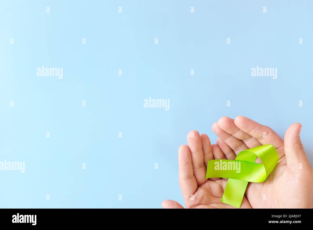 Draufsicht auf das lindgrüne Sensibilisierungsband mit der Hand. Lyme-Borreliose, Psychose, psychische Erkrankungen im Kindesalter, Lymphom und postpartale Depression Pflege Stockfoto