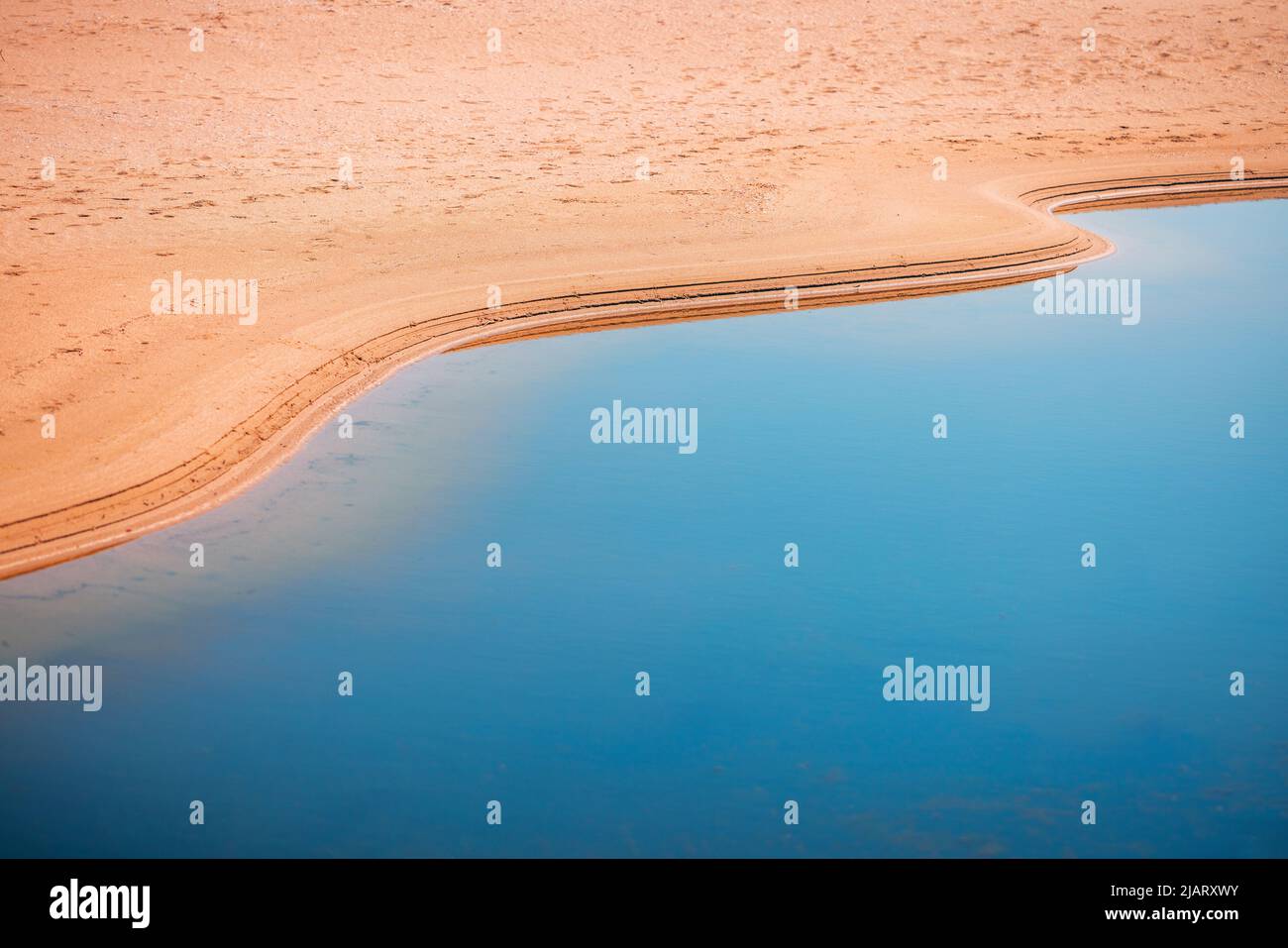 Oase in einer Wüste. Sand und Wasser, Abdrücke von Wellen. Stockfoto Oase in einer Wüste. Sand und Wasser, Abdrücke von Wellen. Stockfoto
