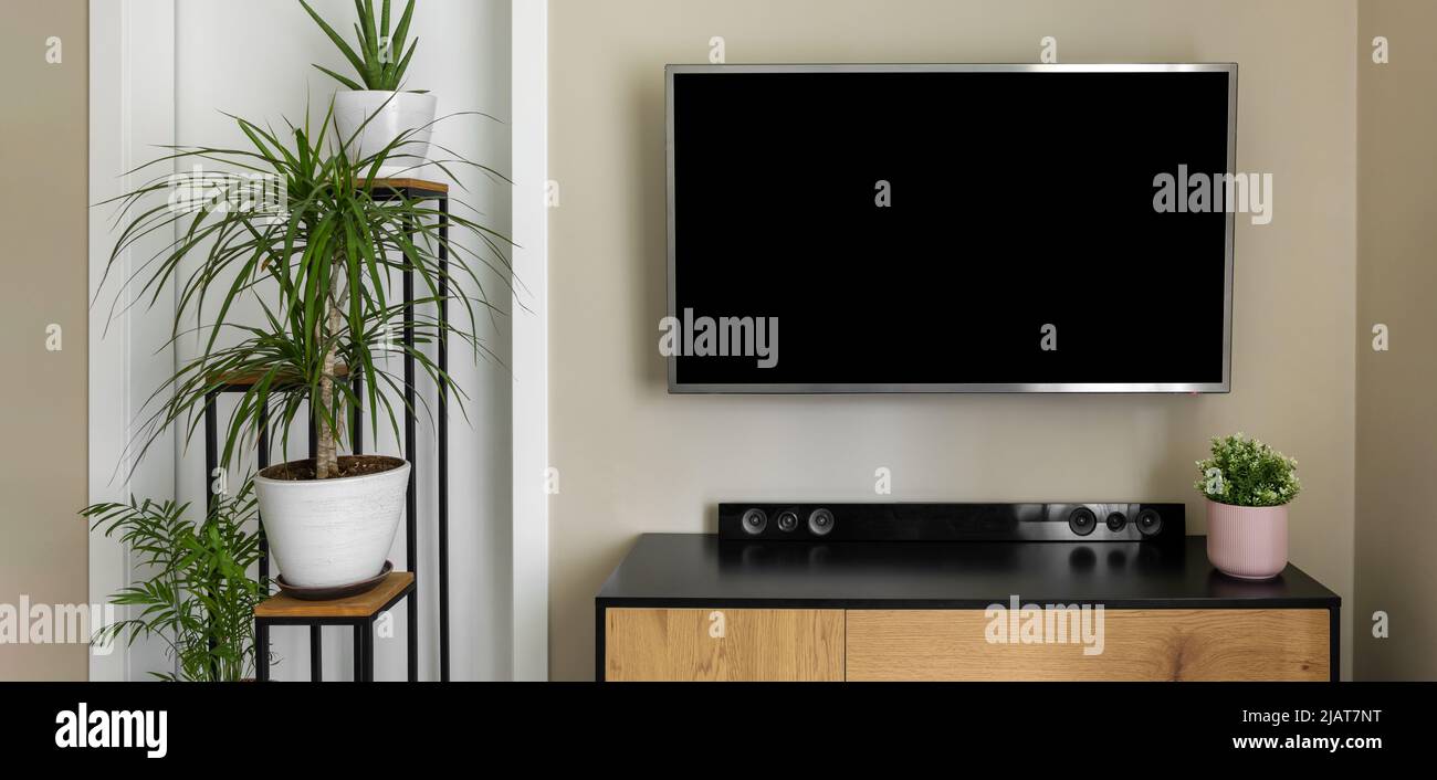 Smart-tv-Modell an beigefarbenen Wänden in moderner Einrichtung mit grünen Pflanzen. Leerer Bildschirm Stockfoto
