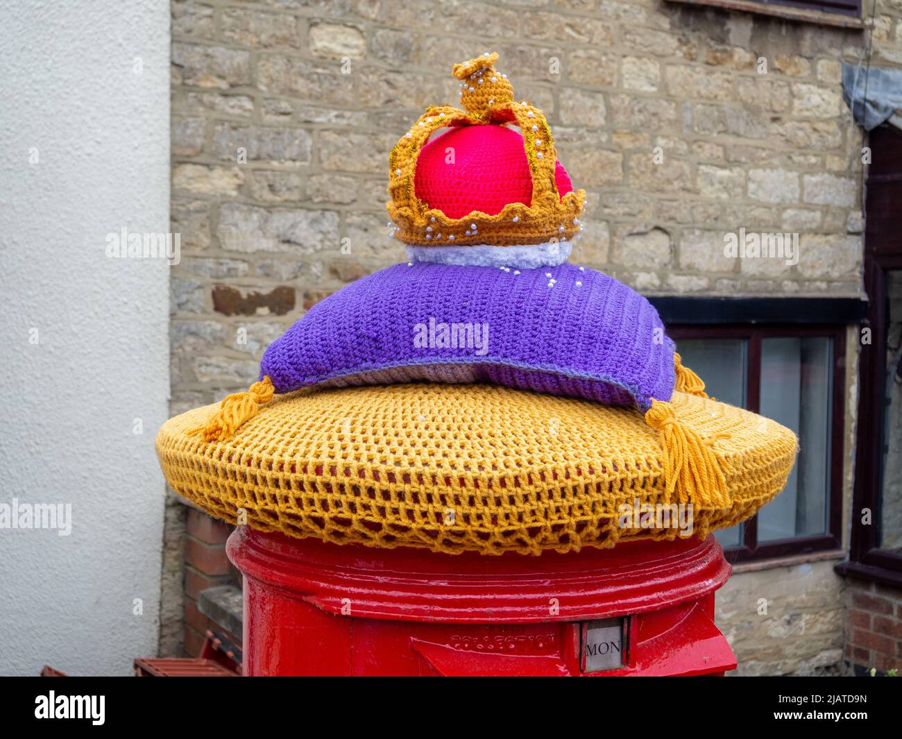 Royal Mail Postbox mit einem gestrickten Oberteil mit einer königlichen Krone zur Feier des Platinum Jubilee der Königin, Hackleton, Northamptonshire, Großbritannien Stockfoto