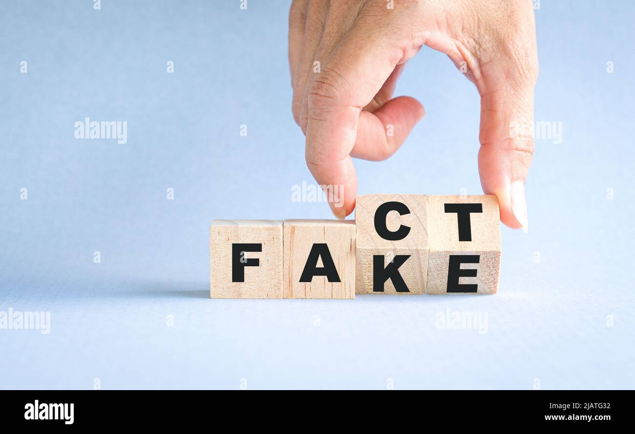 Finger, die Holzwürfel drehen, blockieren, von Fakten bis zu falschen Formulierungen. Stockfoto