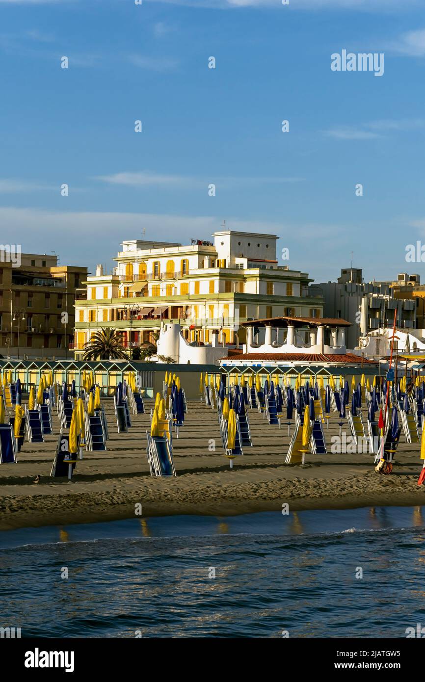 Linien von strahlend gelben und dunkelblauen Schirmen und Liegestühlen am Strand von Ostia, Rom, Italien, Europa, Europäische Union, EU Stockfoto