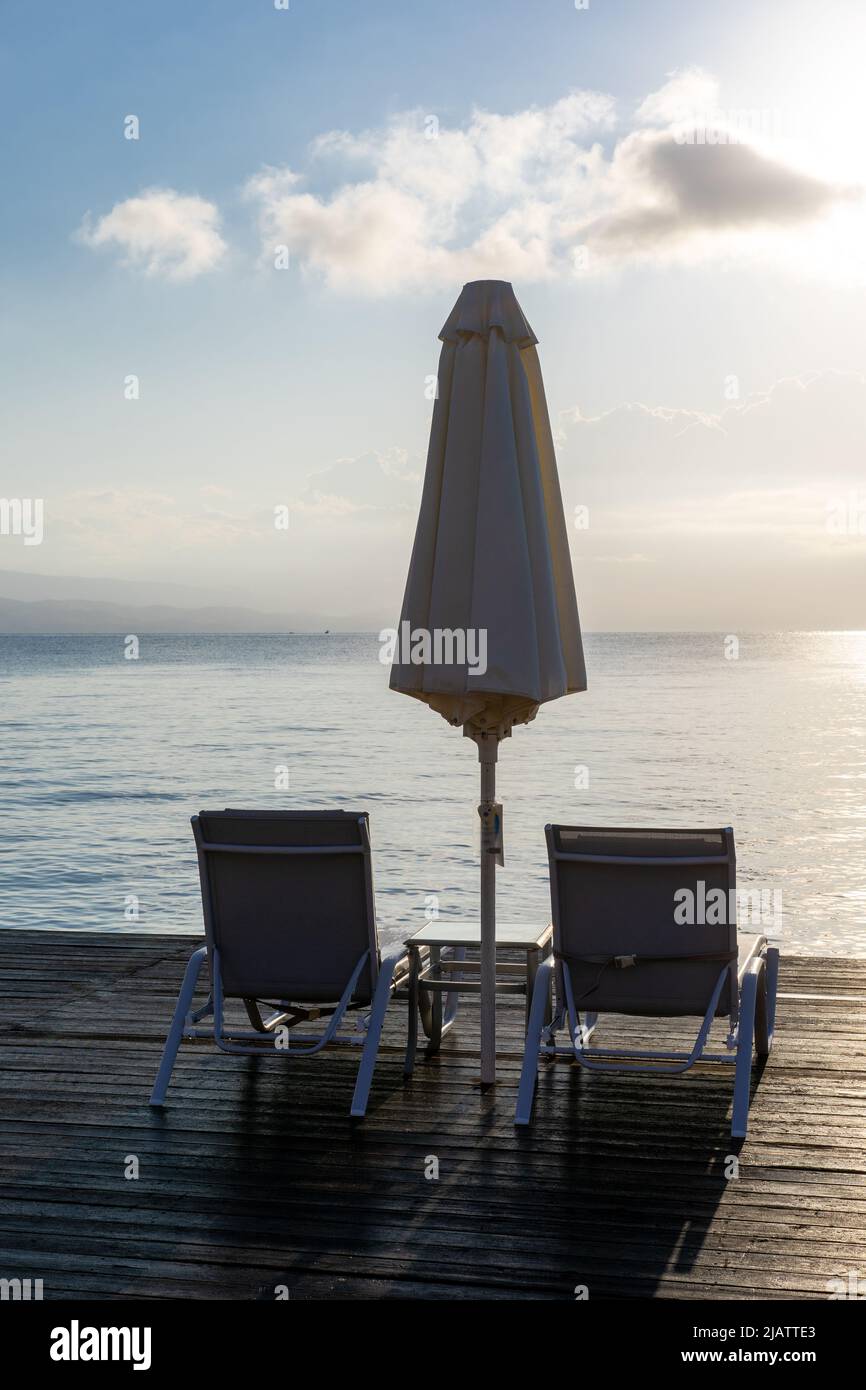 Leere Sonnenliegen am Meer bei Sonnenaufgang Stockfoto