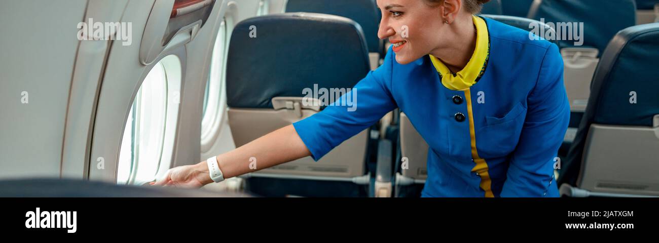 Fröhliche Stewardess, die im Flugzeug aus dem Fenster schaute Stockfoto