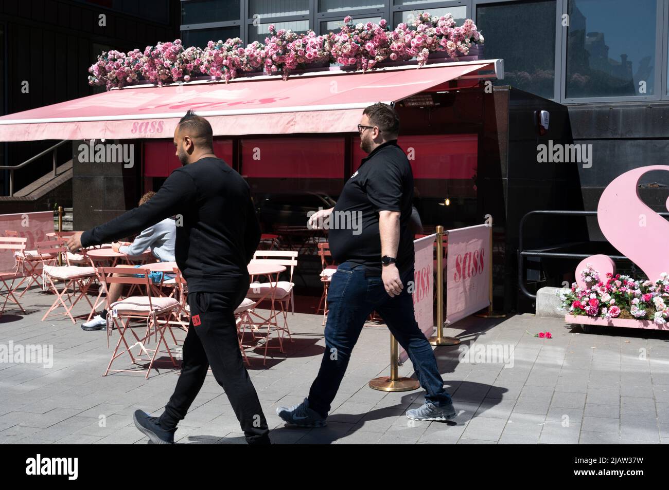 Liverpool, England, Großbritannien. Zwei Männer gehen an einer rosa gestrichenen Bar vorbei. Stockfoto