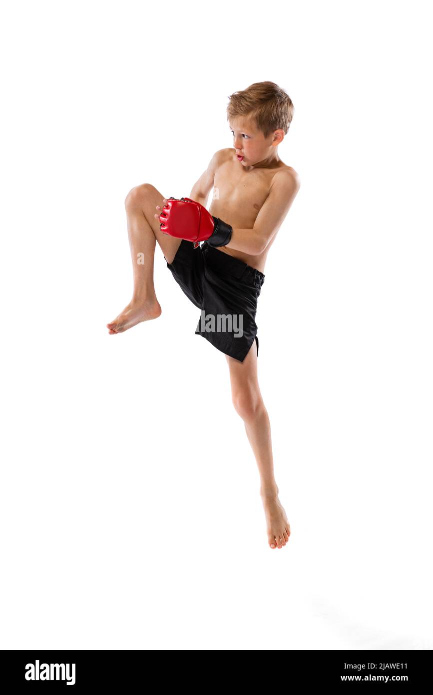 Kleiner Junge, Kind in Sportaufnahmen und Handschuhe üben thai-Boxen auf weißem Studiohintergrund. Sport, Bildung, Action, Bewegungskonzept. Stockfoto