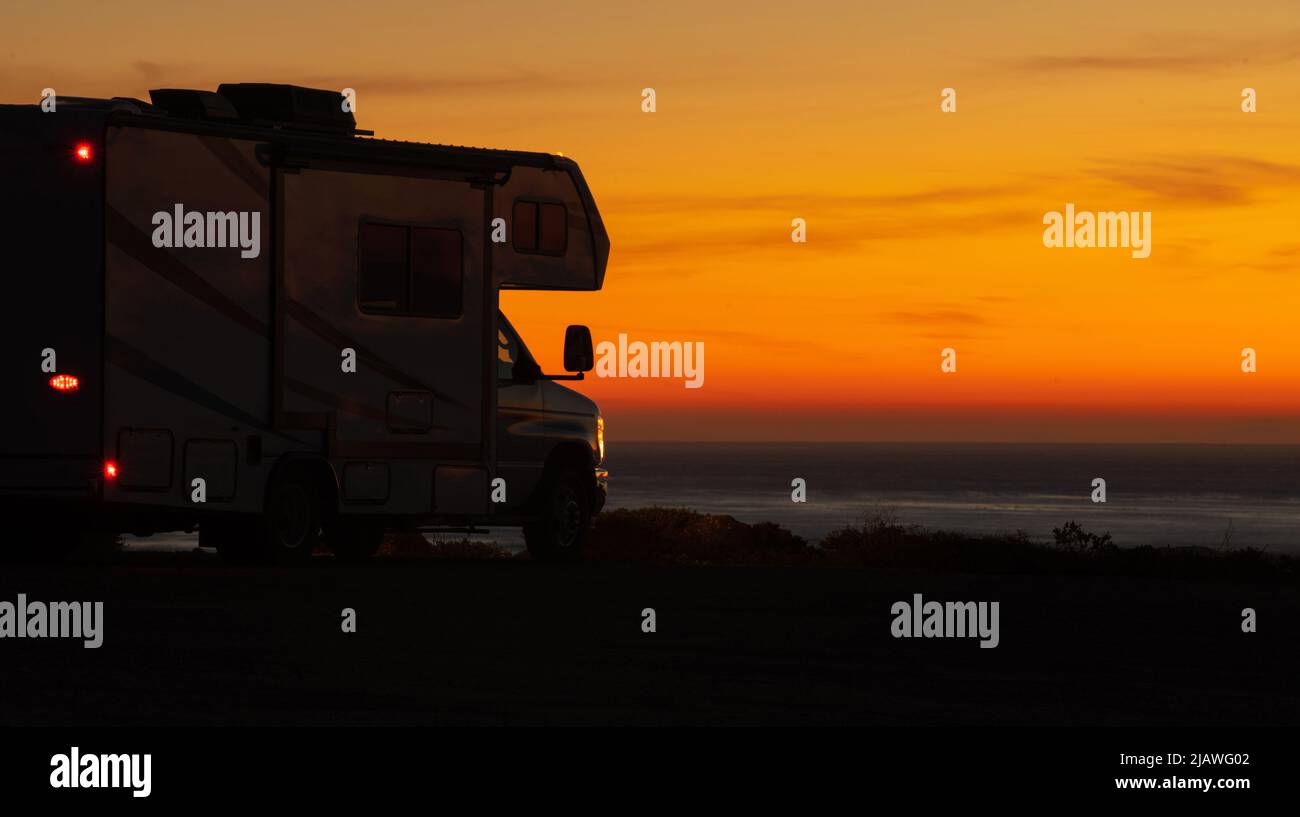 Landschaftlich schöner, trockener Camping am Meer bei Sonnenuntergang in einem modernen Wohnmobil der Klasse C. Vermietung von Freizeitfahrzeugen und Road Trip. Stockfoto