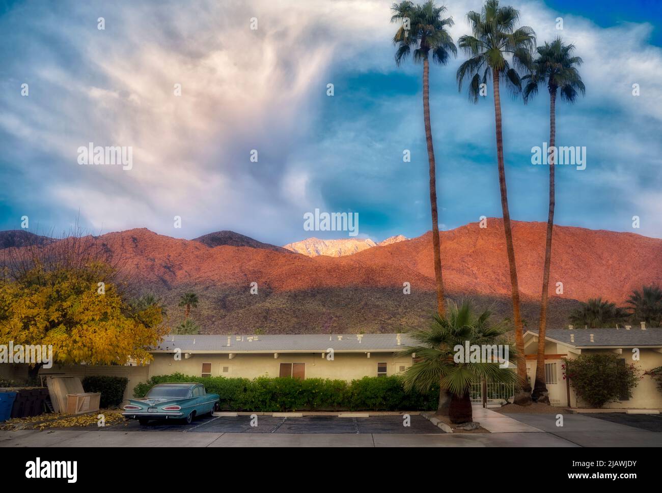 Schnee, Sonnenaufgang, altes Auto und Hotel und Palmen auf San Jacinto Mountains. Palm Springs, Kalifornien Stockfoto