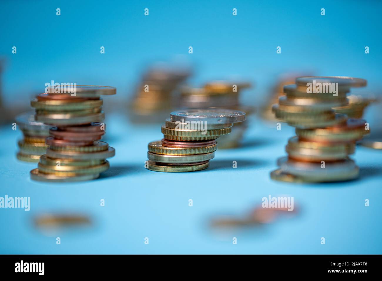 Auf blauem Hintergrund stapelten sich Münzen. Euro-Münzen aus der Europäischen Union. Geld und Bargeld stapelten sich bis zu Türmen Stockfoto