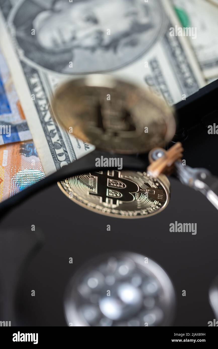 Bitcoin, der auf der Festplatte reflektiert wird. Digitale Krypto-Währung auf Festplatte und Dollarnoten im Hintergrund. Kryptoabbau und Mininkosten Stockfoto
