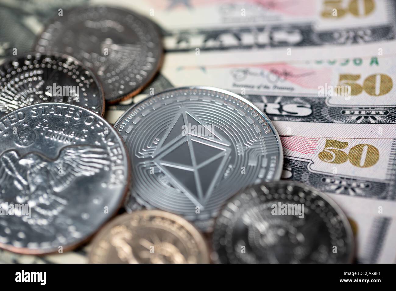 Silber-ethereum-Münze auf fünfzig-Dollar-Banknoten und halben-Dollar-Münzen und Eisenhower-Dollar. Kryptowährungskonzept mit Dollar-Papiergeld Stockfoto