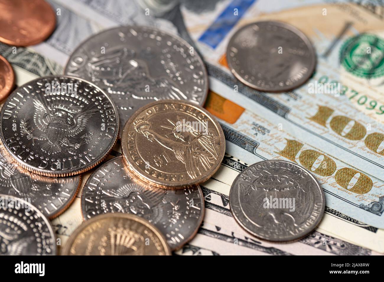 Eineinhalb-Dollar-Münzen auf 100-Dollar-Banknoten. US-Bargeld verteilt sich. Papiergeld und Metallmünzen. Handel in den USA und international Stockfoto