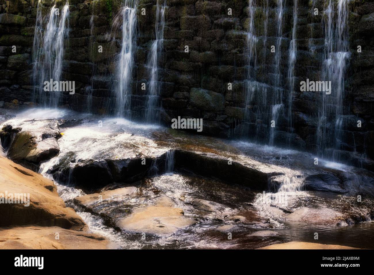 Wasser überläuft den Felsdamm auf die Felsen unterhalb des Yates Mill County Park in North Carolina. Stockfoto