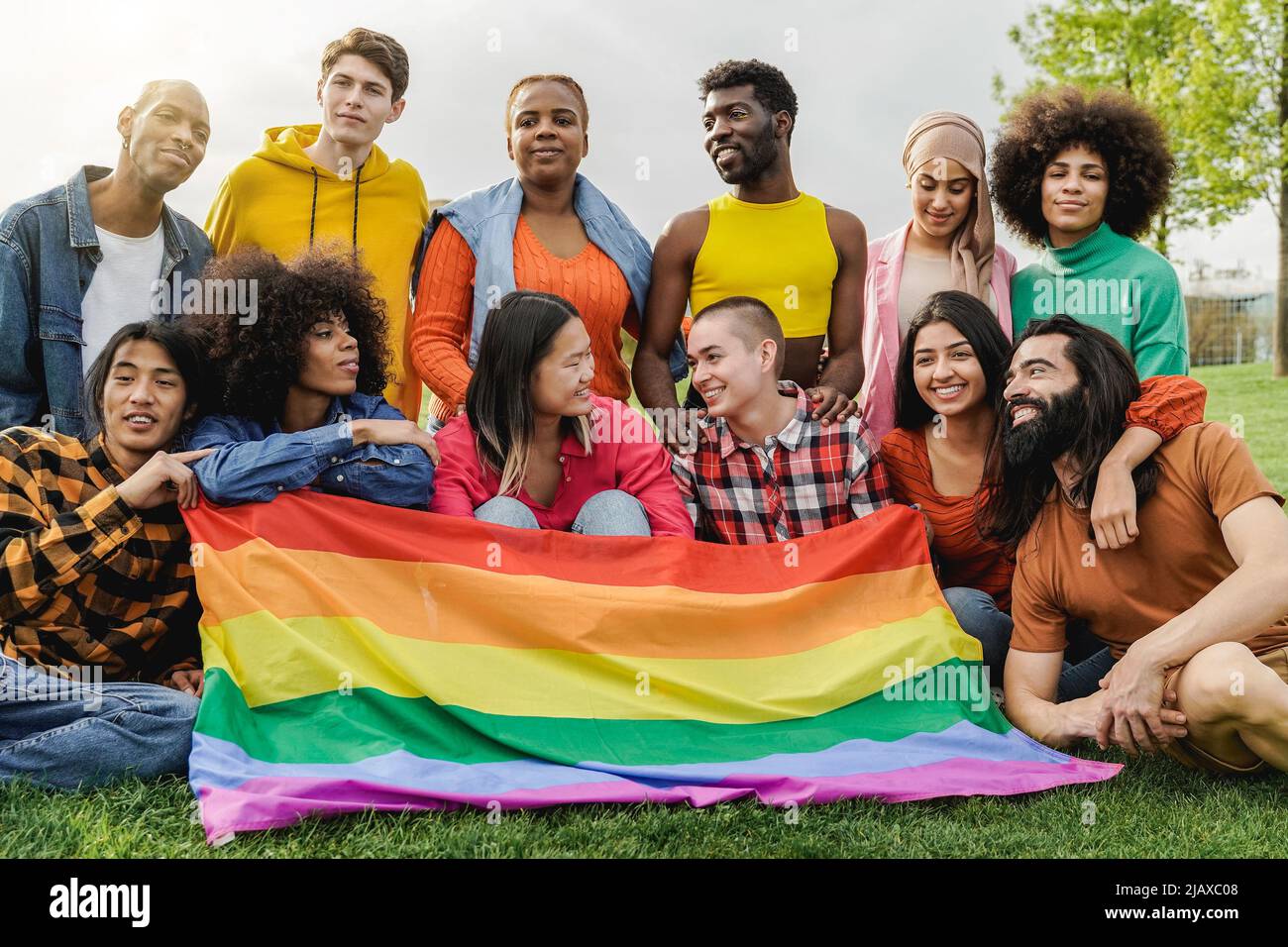 Fröhliche, vielfältige Freunde halten die LGBT-Regenbogenfahne und haben gemeinsam Spaß im Freien - Schwerpunkt auf Glatze Girl Face - Diversity Community-Konzept Stockfoto