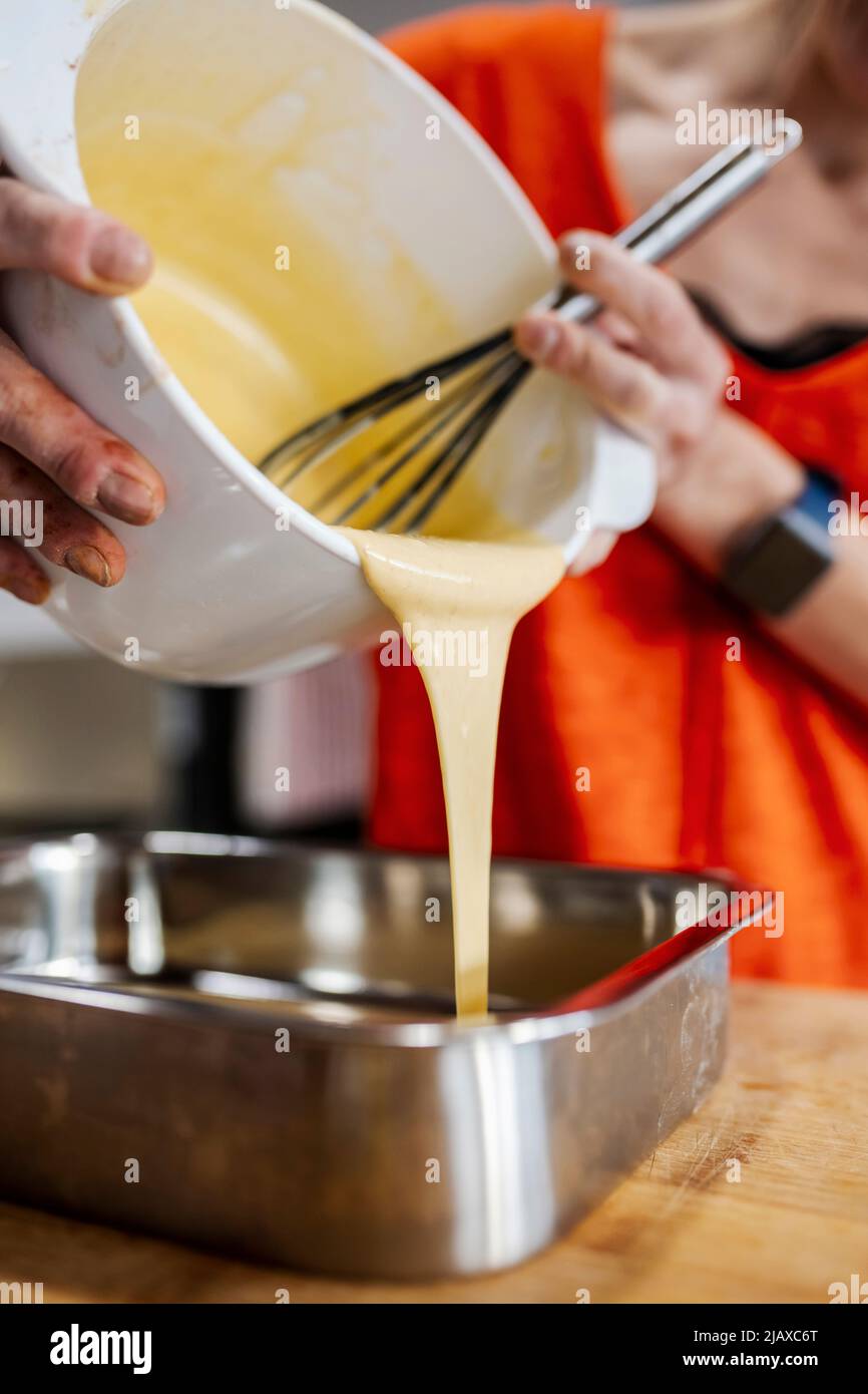 Frau gießt flüssiges Mousse in eine Form. Stockfoto