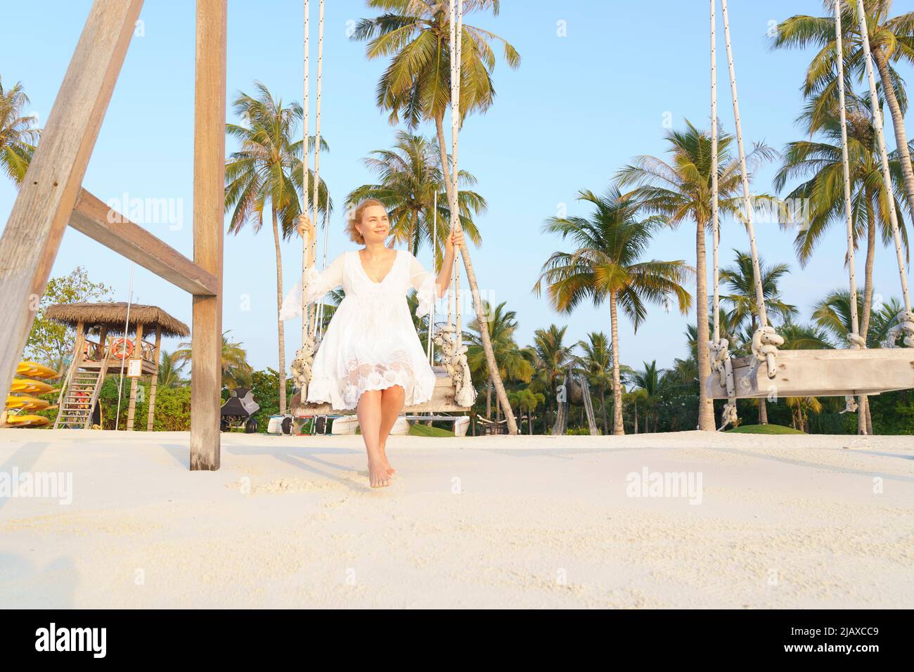 Eine Frau schwingt auf einer Schaukel am Strand. Stockfoto