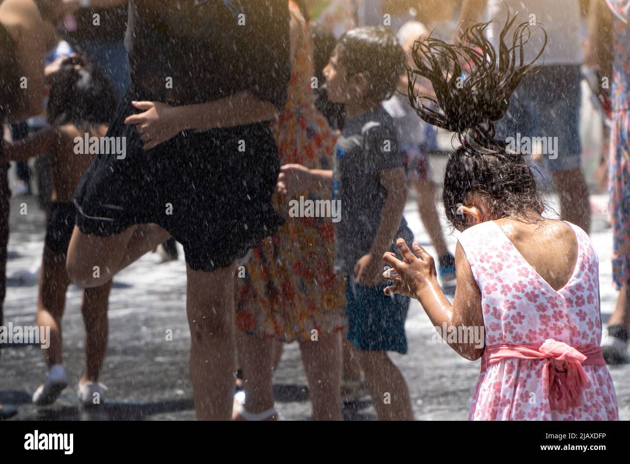 Kinder verschiedener Ethnien spielen auf der Straße mit Wasser und Schaum, der von Feuerwehrleuten auf einer lokalen Party geworfen wird Stockfoto
