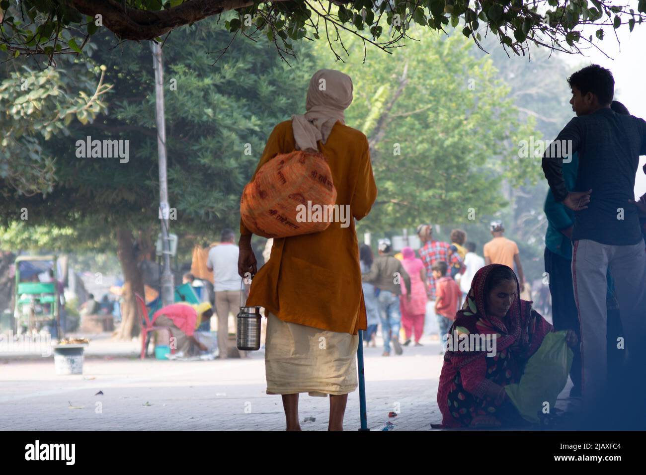 Sadhu Mönch trägt die Safranroben heilig zum hinduismus und eine Tasche mit heiligen Symbolen beim Gehen unter den Menschen am Ufer des heiligen Flusses ganga Stockfoto