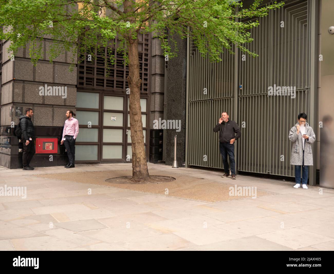 Gruppe von Rauchern, die während der Pause vor dem Büro in Central London Zigaretten rauchen Stockfoto