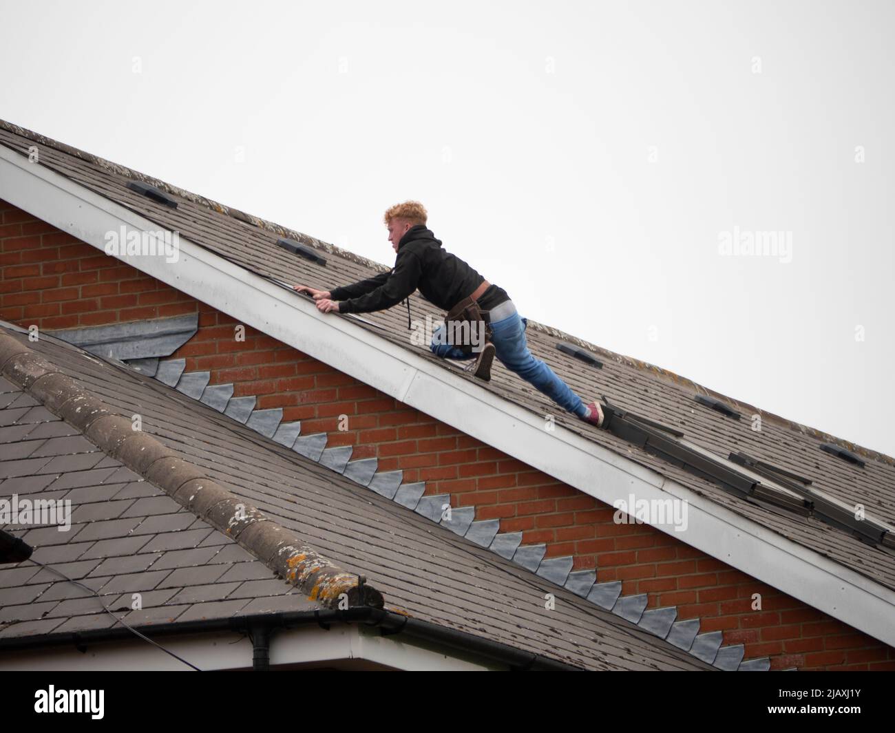 Dachdecker, die in der Höhe arbeiten und Fliesen auf dem Dach im Nordosten Londons befestigen Stockfoto