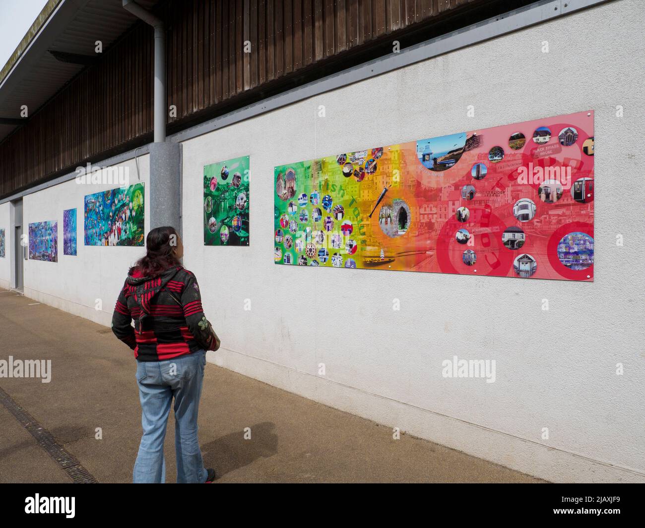 Frau mit Blick auf die öffentliche Kunst an der New Fish Market Wall, Brixham, Devon, Großbritannien Stockfoto