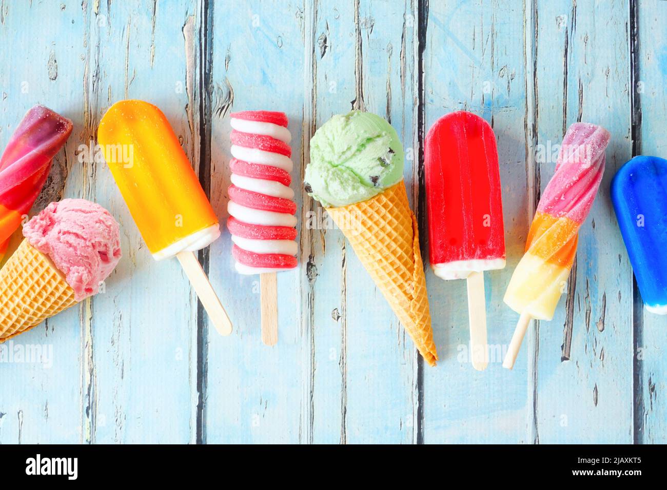 Auswahl an farbenfrohen Sommerpopsicles und Eiscreme-Leckereien. Ansicht von oben auf einem rustikalen blauen Hintergrund verstreut. Stockfoto