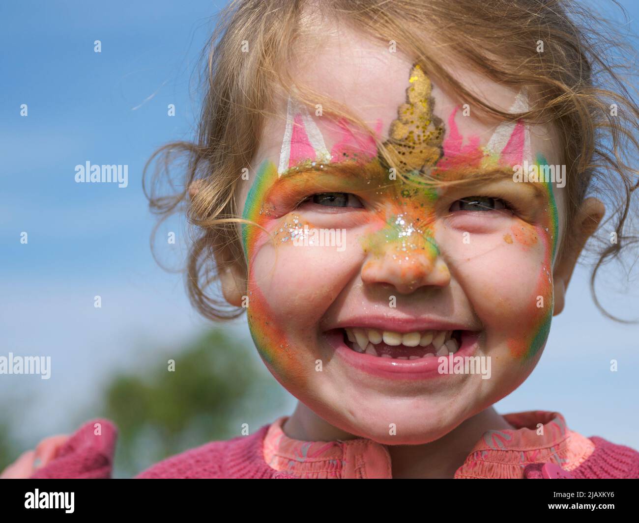 Junges Mädchen mit Gesicht gemalt glücklich und lächelnd, Großbritannien Stockfoto