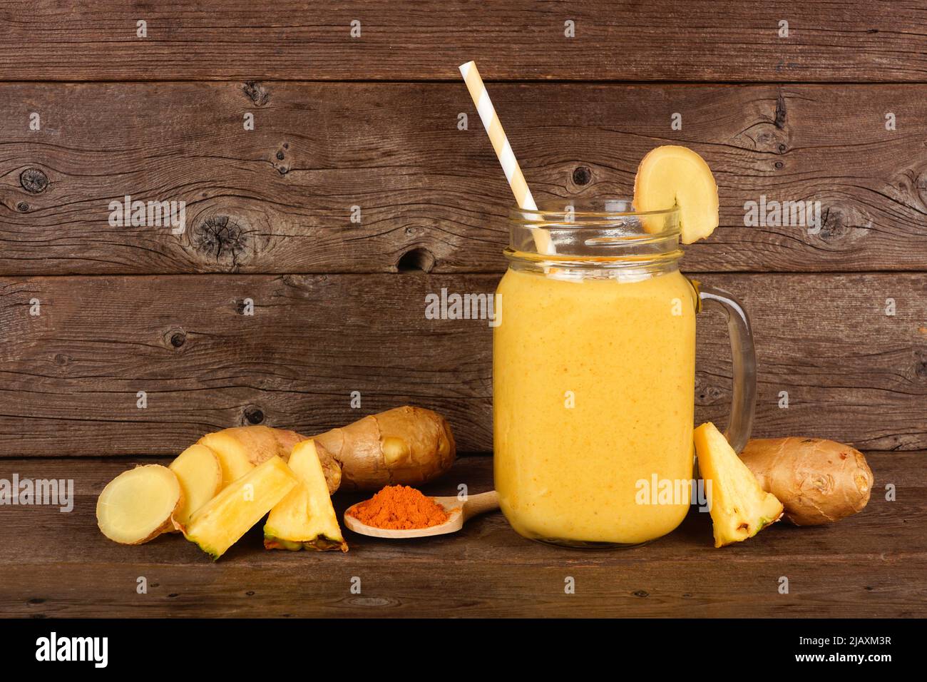 Ananas, Kurkuma, Ingwer-Smoothie in einem Einmachglas vor dunklem Holz mit Zutaten. Gesunde Immunantwort, Gewichtsverlust, Anti-Inflam Stockfoto