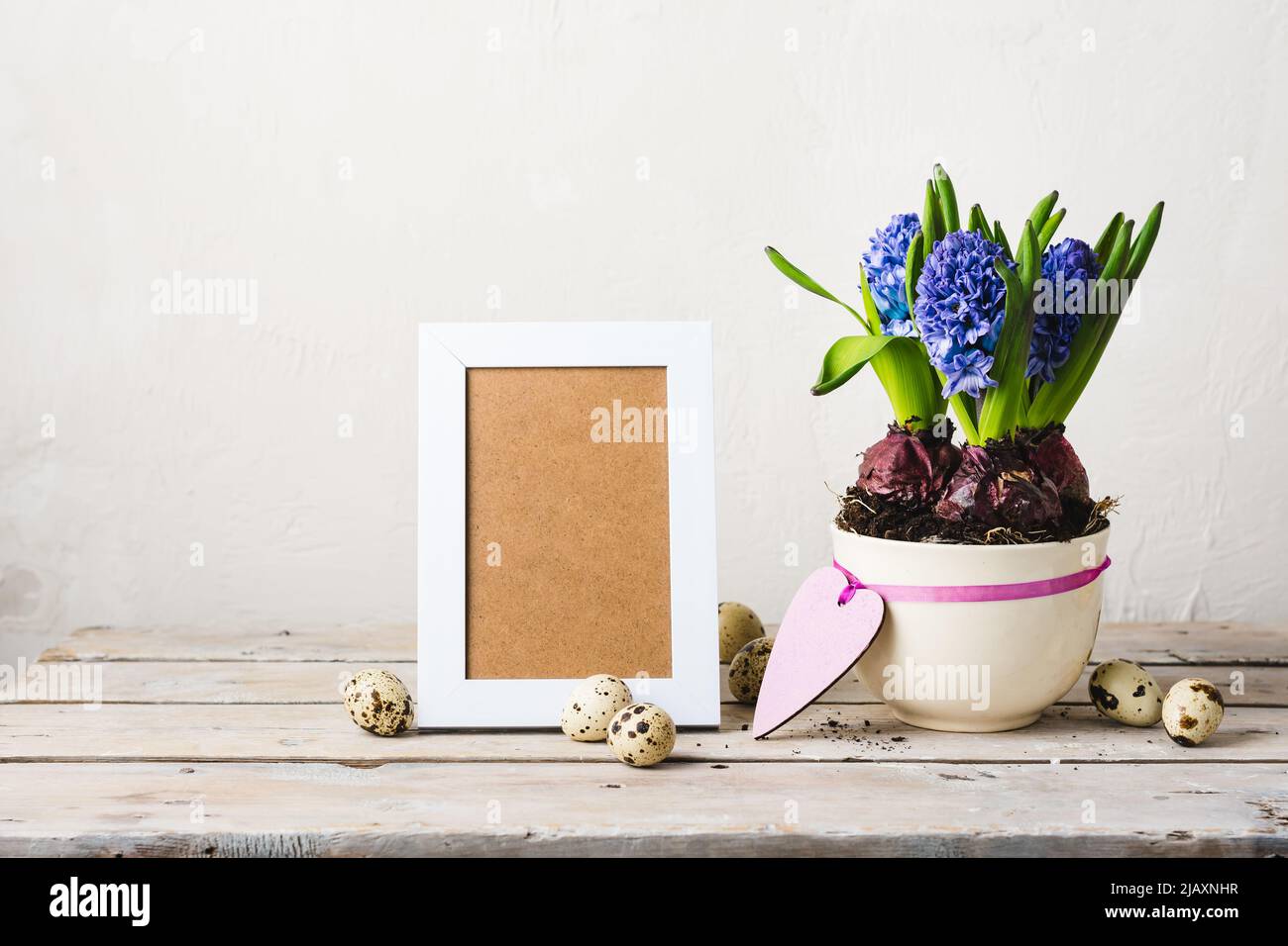 Blaue Hyazinthen, Fotorahmen und Wachteleier auf einem Holztisch. Stockfoto