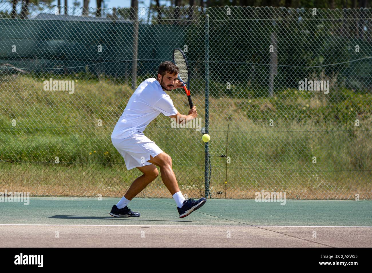 Tennisspieler trifft mit Schläger auf dem Platz auf die Rückhand beim Ball. Stockfoto