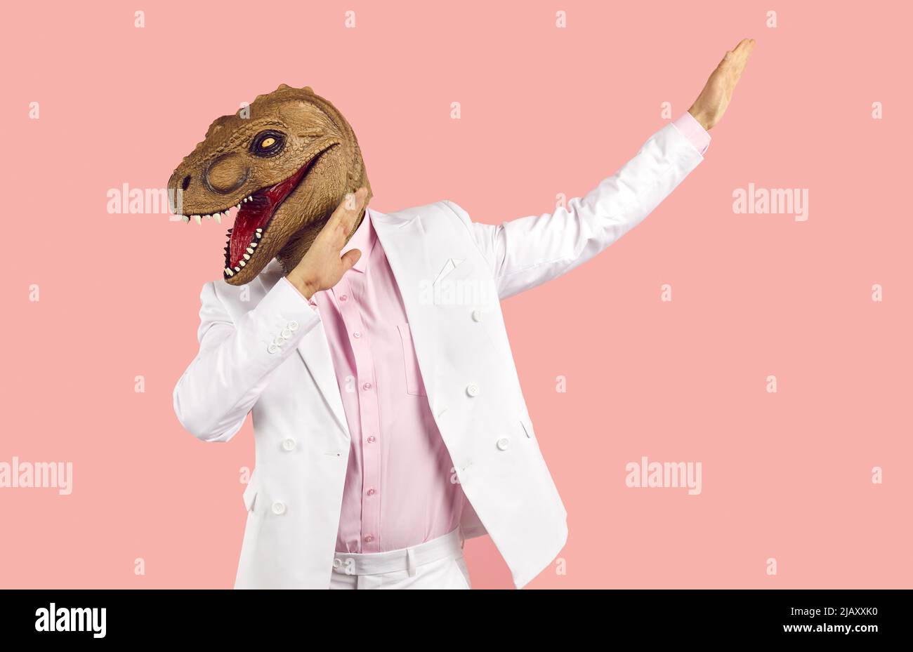 Seltsamer Kerl mit Anzug und witziger Dinosaurier-Maske, tanzt und hat Spaß auf einer verrückten Party Stockfoto