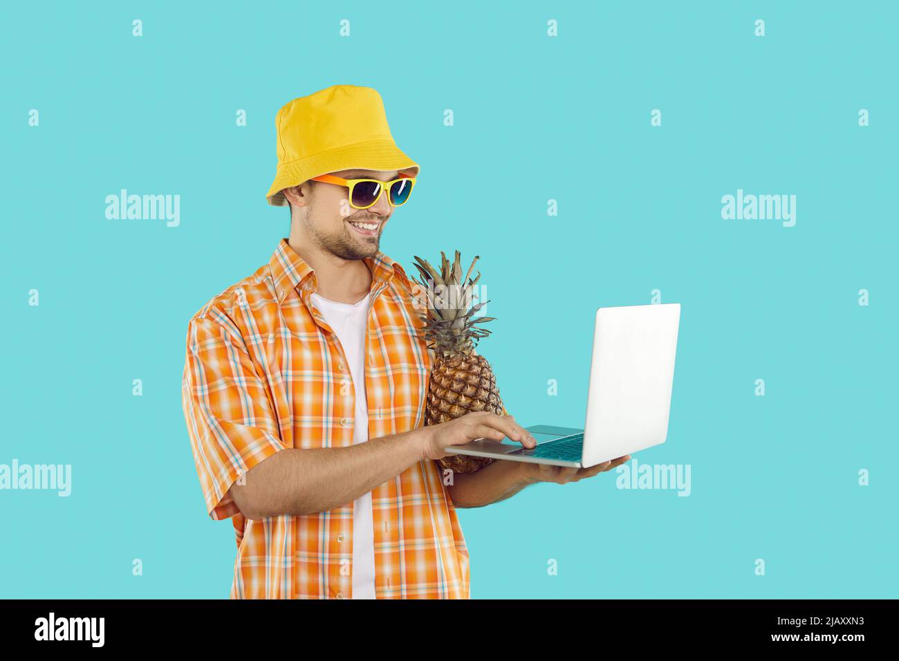 Glücklicher männlicher Freiberufler mit Laptop in den Händen, der während der Sommerferien online arbeitet. Stockfoto