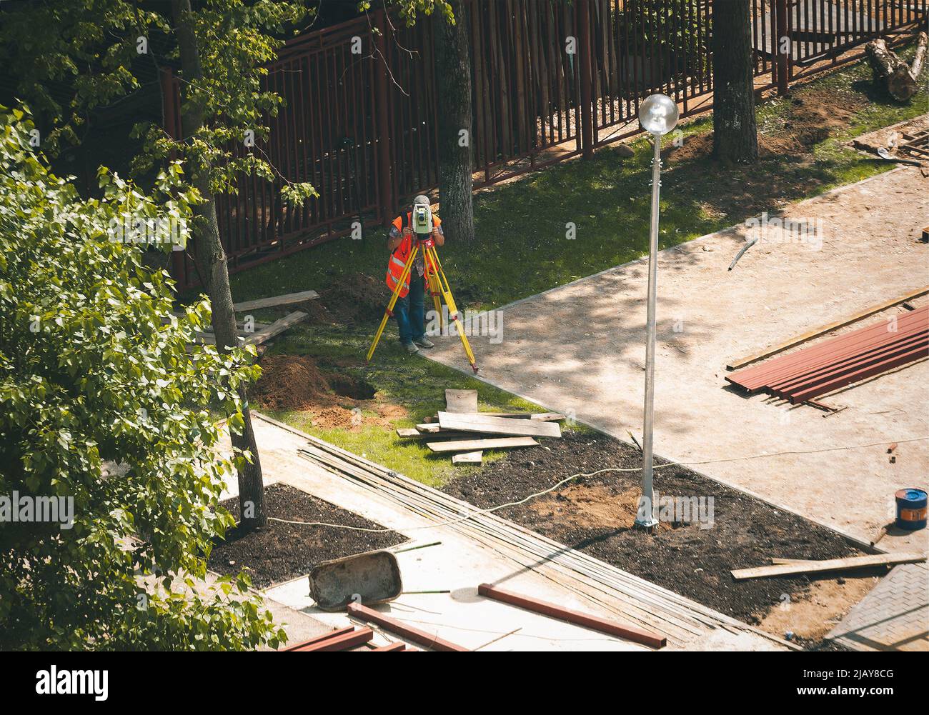 Der junge Ingenieur nutzt die Total Station (Tacheometer, Theodolit) bei der Gestaltung städtischer Landschaftsgestaltung Stockfoto