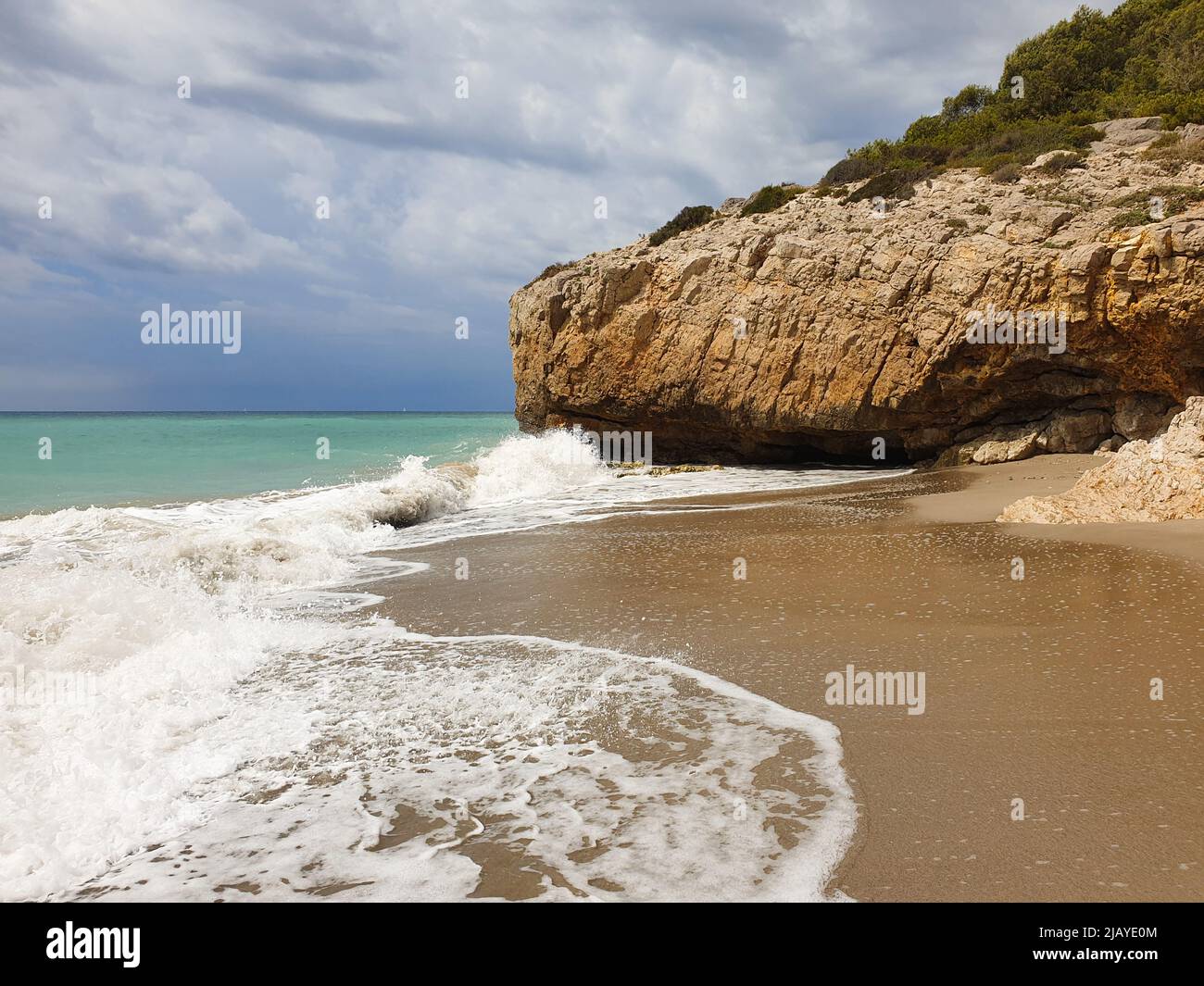 Sandstrand mit türkisfarbenem Meer vor dem Sturm, bewölktem Himmel, Sitges, Spanien Stockfoto