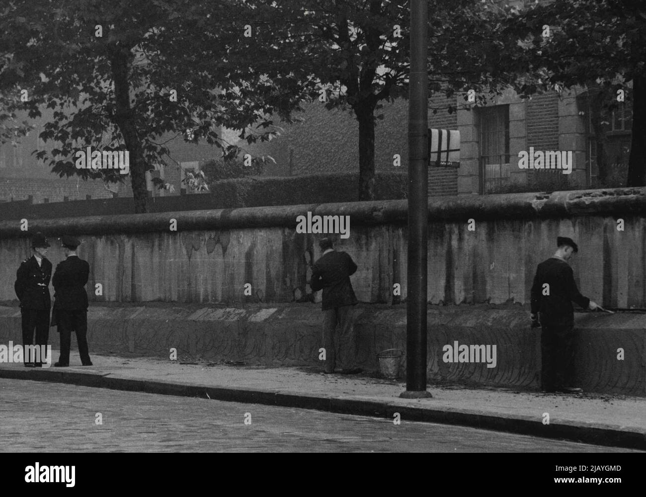 Menschenmassen verhöhnten die Sträflingsbande - in einer geschäftigen Londoner Straße spielten gestern Kinder um die Füße von Gefangenen aus einem der härtesten Gefängnisse Großbritanniens. In blauem Gefängnisgewand gekleidet und von uniformierten Aufsehern überwacht, reparierten die Männer die Außenwand des Gefängnisses von Pentonville - wo Anfang des Jahres der Massenmörder Christie gehängt wurde. Samstagmorgen gingen die Käufer um die Männer und ihre Kinder spielten in der Nähe, zwei kleine Kinder, ein Mädchen und ein Junge, rannten zu den Gefangenen und schrien ihnen etwas zu. Einer der Gefangenen lächelte, der andere lächelte. 04. Oktober 1953. (Foto von Paul Po Stockfoto