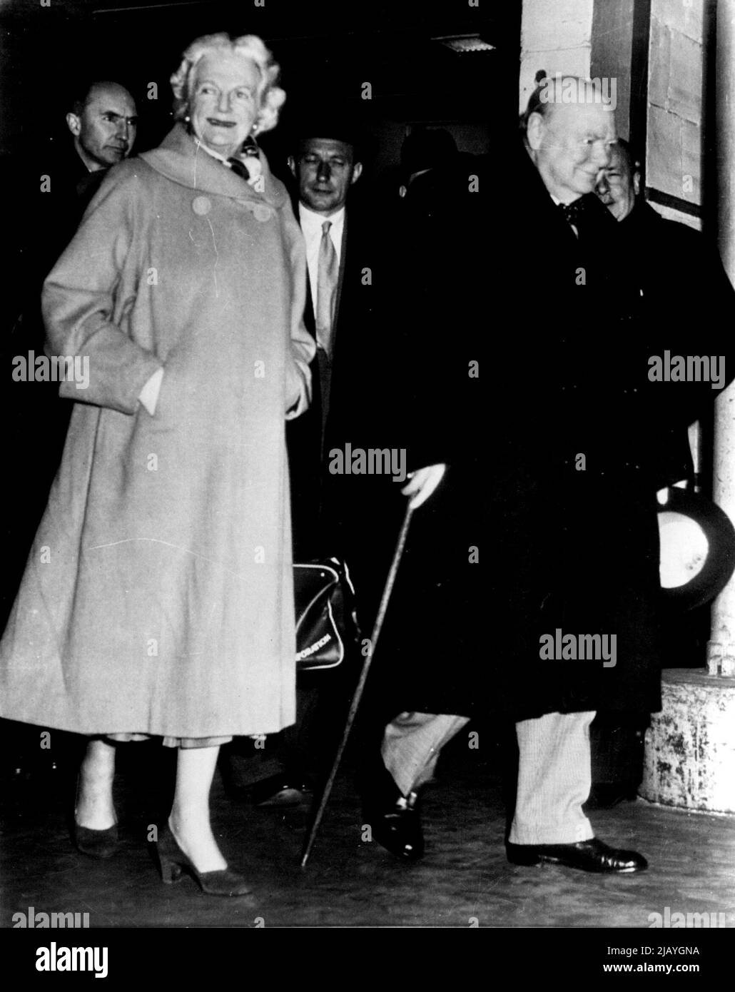 Der Urlaub für Winnie ist vorbei: Der britische Premierminister Winston Churchill und Mrs. Churchill gehen heute hier in Richtung der Gangplanke des Liners Queen Mary, während sie sich nach einem Urlaub in Westindien auf die Heimreise vorbereiten. Dem Paar, mit dem Kopf hinten links entblödet, folgt der britische Botschafter in den USA, Sir Roger Makins, der Churchill bei ihrer Ankunft mit dem Flugzeug aus Jamaika traf und sie zu dem Schiff in der Mitte hinten eskortierte, ist nicht identifiziert. 23. Januar 1953. (Foto von AP Wirephoto). Stockfoto