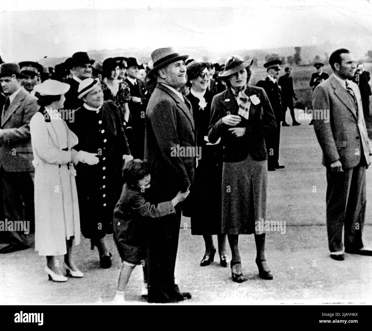 Il Duce wartet auf die Begrüßung seiner Söhne: Il Duce und Mitglieder seiner Familie werden hier gezeigt, als sie auf dem Flughafen warteten, um seine beiden Söhne und seinen Schwiegersohn Graf Ciano nach ihrer Rückkehr aus dem Äthiopienkrieg zu begrüßen. Mussolini wird beim Spielen mit seiner Tochter Anna Maria gesehen. Links hinten von Il Duce befinden sich Gräfin Ciano, seine Tochter und Signora Mussolini. 25.Mai 1936. (Foto von Associated Press Photo). Stockfoto