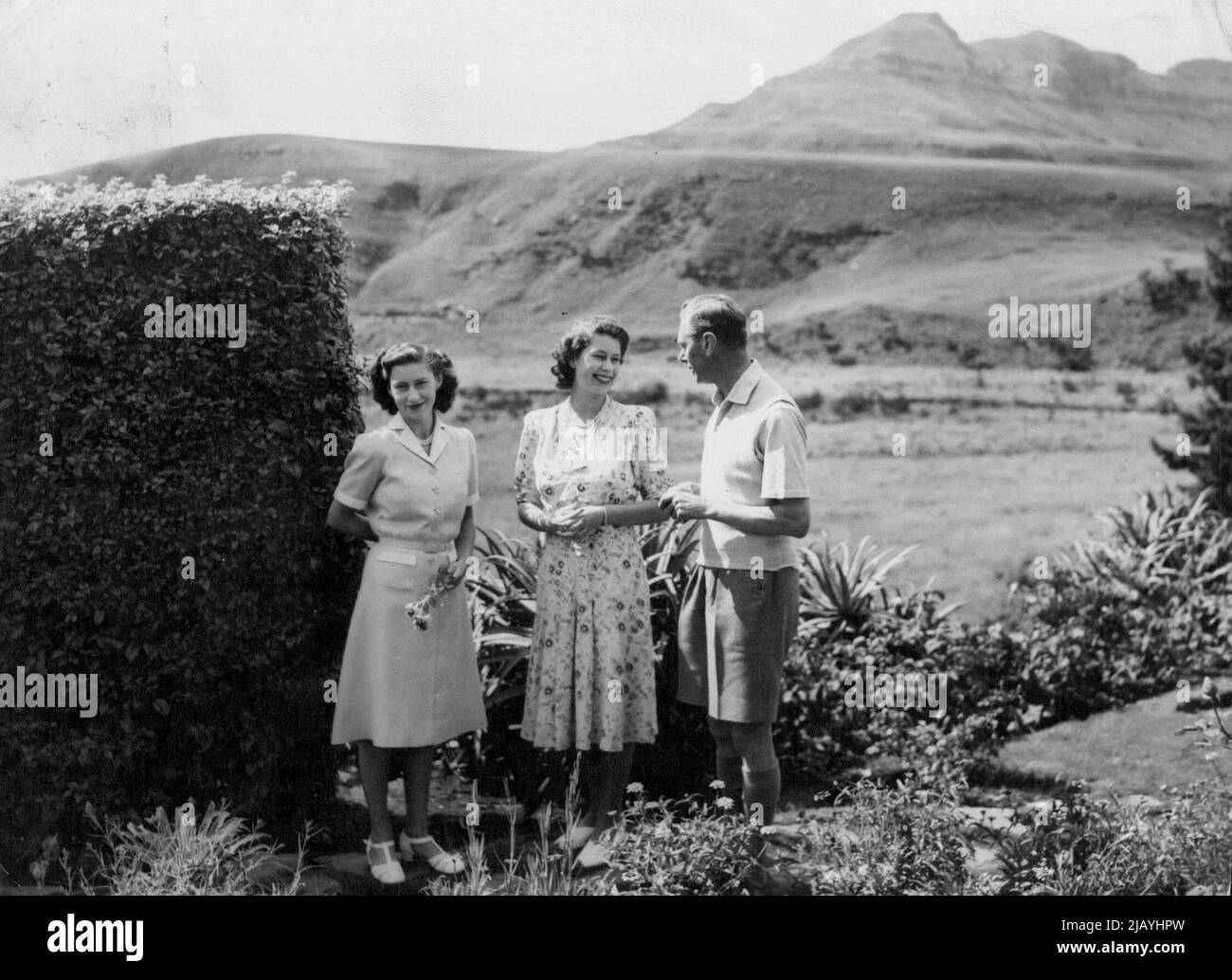 Der König und seine Töchter im Urlaub in Natal -- Prinzessin Elizabeth lächelt den König im ***** an Räume des Natal-Nationalparks. Auf der linken Seite, ***** Eine Blume, ist Prinzessin Margaret. Die überfüllte südafrikanische Tour der britischen Königsfamilie wurde für vier Tage unterbrochen, während König George, Königin Elizabeth und ihre Töchter, Prinzessin Elizabeth und Margaret eine wohlverdiente Pause im Natal-Nationalpark machten, der an der Grenze zu Natal-Basutoland 60 Meilen südwestlich von Ladysmith liegt. Die Königliche Partei wohnte in einem Thatchod-Hostel am Fuße der Drakensburger Berge, von wo aus sie es konnten Stockfoto