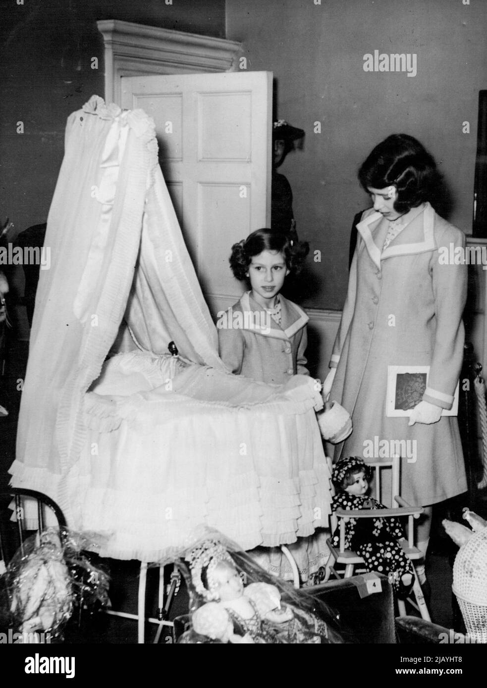 Prinzessinnen sehen ihr eigenes Kinderbett auf der Ausstellung -- Prinzessin Elizabeth (rechts ***** Prinzessin Margaret Rose beim Betrachten des ***** Beide werden als Babys verwendet und das ist jetzt ***** War früher ihre Kinderstube. Prinzessin Elizabeth und Prinzessin Margaret Rose besuchten ihr altes Haus. No.145, Piccadilly, Londoner Residenz des Königs und der Königin als Herzog und Herzogin von York, um die Ausstellung der königlichen und historischen Schätze zu sehen, zu der sie zusammen mit anderen Mitgliedern der königlichen Familie Exponate beisteuerten. Die Königin besuchte vor kurzem die Ausstellung mit dem König und war so beeindruckt, dass sie entschied, dass die Princesse Stockfoto