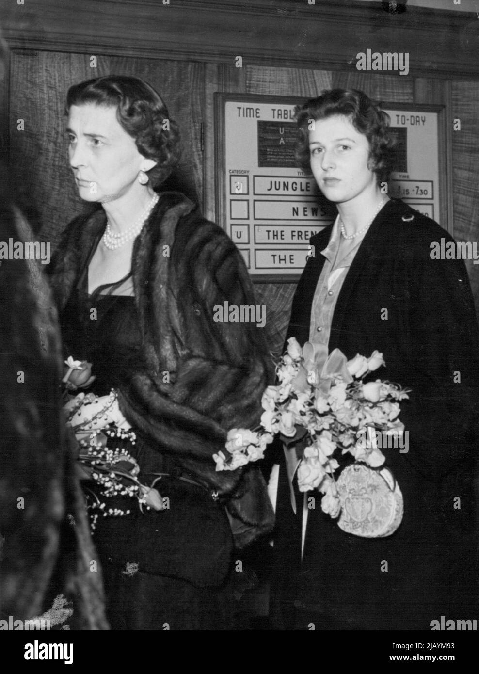 Royal Racegoers in the Ascot Breeze -- die Herzogin von Kent legt eine zurückhaltende Hand an ihren Hut, gefangen vom frischen Brühchen, während sie mit ihrer Tochter Prinzessin Alexandra den Kurs bei ihrer Ankunft in Ascot heute (Dienstag) hinunterfährt. 15. Juni 1954. (Foto von Reuterphoto) Stockfoto