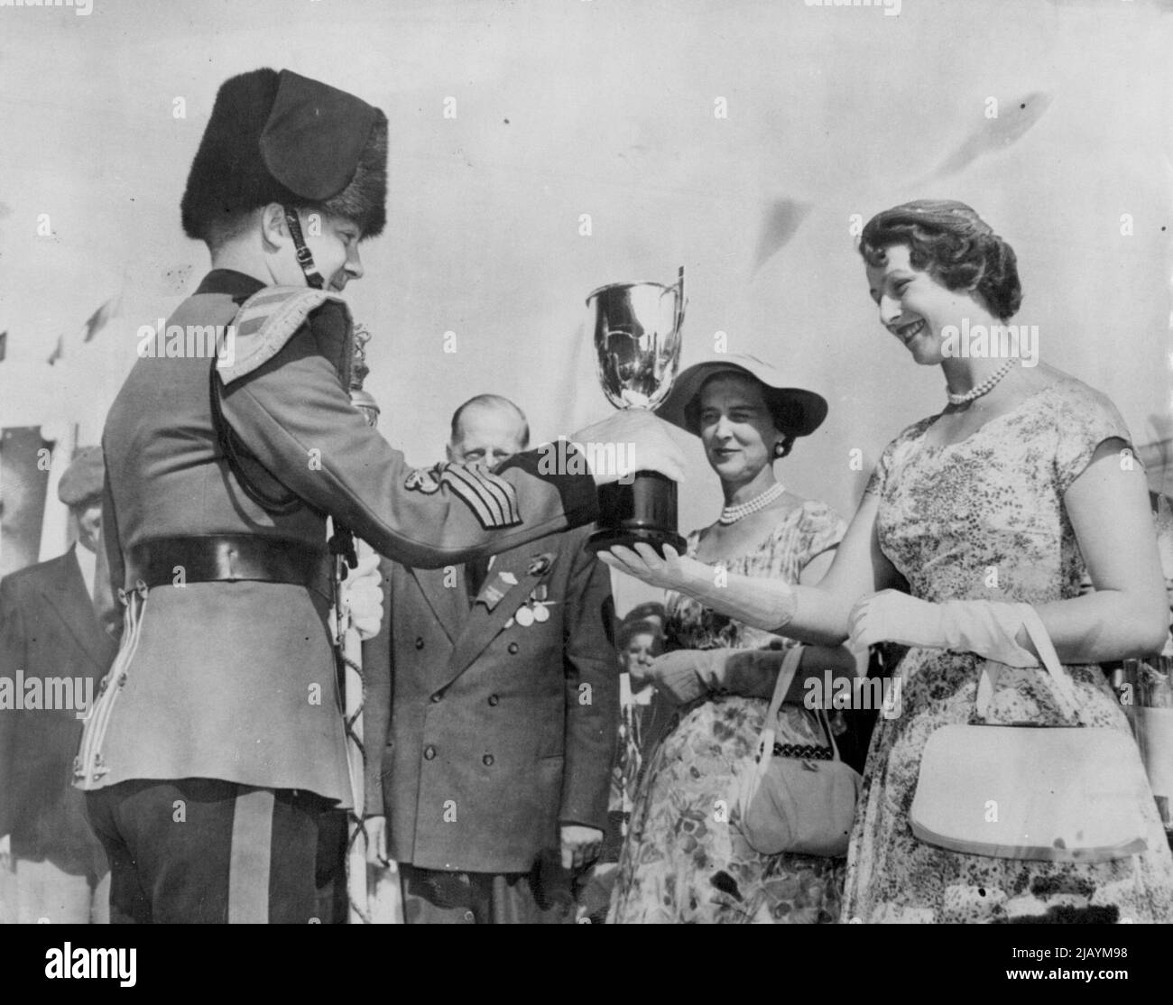 Prinzessin Macht Präsentation -- Prinzessin Alexandra, die von ihrer Mutter, der Herzogin von Kent, beobachtet wird, überreicht den Pokal an Trompete-Major A. F. Smith von der zweiten Signal Regiment-Trompete-Band während der Warriors Day-Zeremonien auf der Canadian National Exhibition, die von den königlichen Besuchern während ihres Besuchs in Toronto auf ihrer kanadischen Tour eröffnet wurde. 04. September 1954. (Foto von Reuterphoto) Stockfoto
